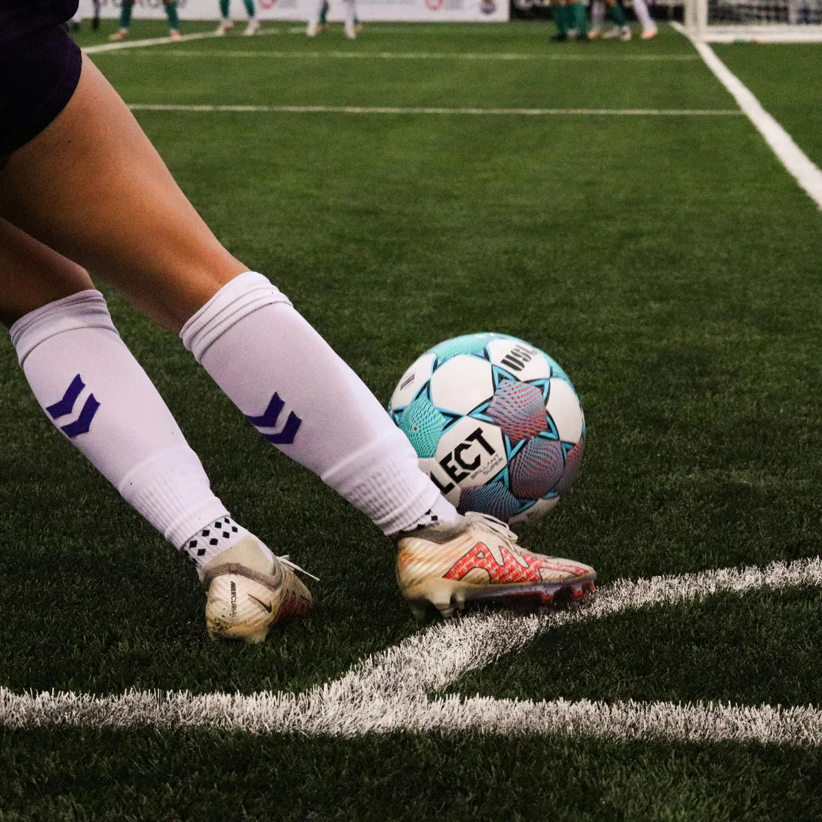 Primer plano de un futbolista ejecutando un córner junto a la línea de esquina